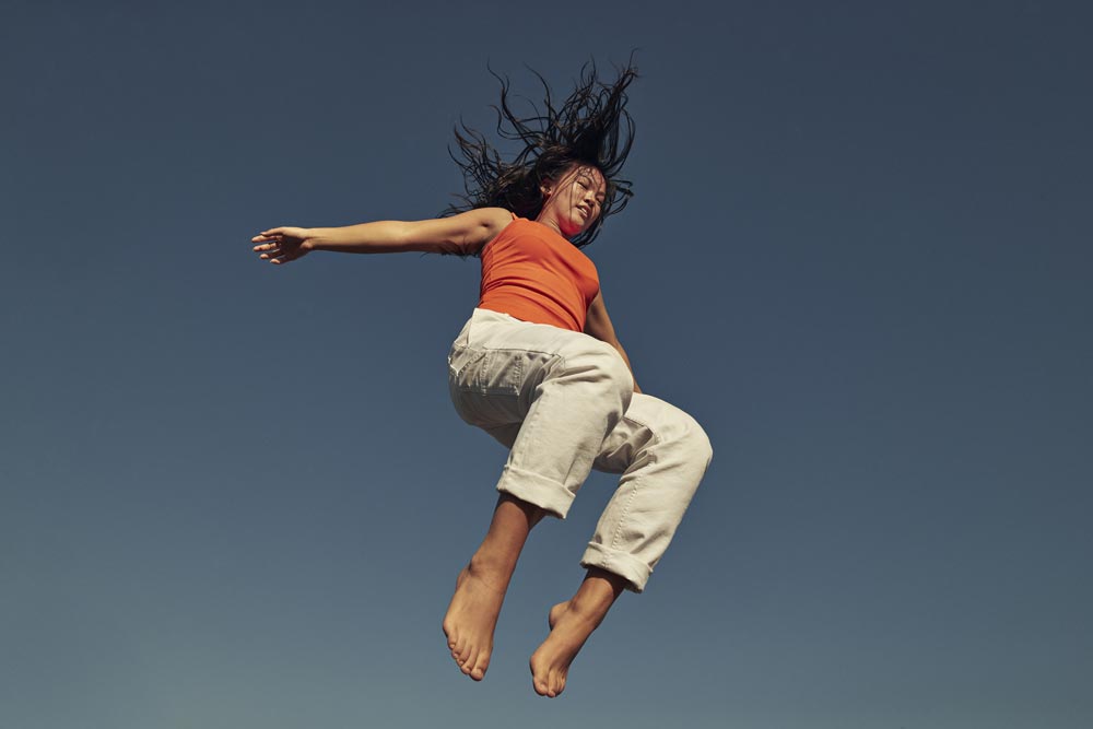 Kvinna som hoppar med himmel i bakgrunden