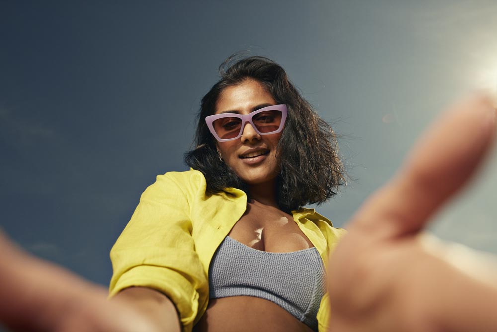Kvinna som posear mot kameran i solglasögon